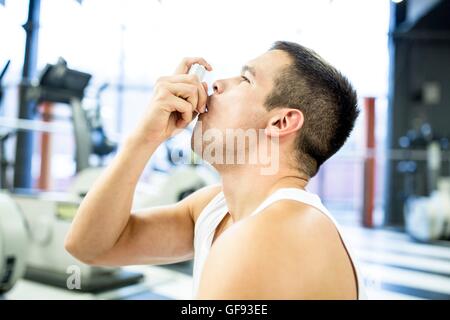 PROPERTY RELEASED. MODEL RELEASED. Young man using inhaler in gym. Stock Photo