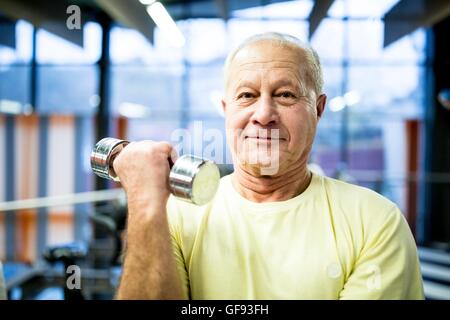 PROPERTY RELEASED. MODEL RELEASED. Portrait senior man holding dumbbell in gym. Stock Photo
