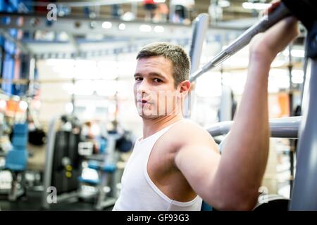 PROPERTY RELEASED. MODEL RELEASED. Portrait of young man using exercising machine in gym. Stock Photo