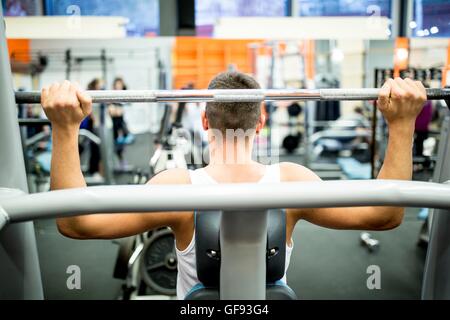 PROPERTY RELEASED. MODEL RELEASED. Young man using exercising machine in gym. Stock Photo