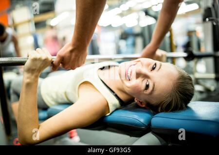 PROPERTY RELEASED. MODEL RELEASED. Young woman using exercising machine and smiling in gym. Stock Photo