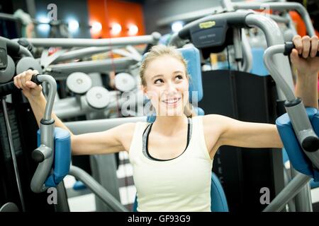 PROPERTY RELEASED. MODEL RELEASED. Young woman using butterfly machine in gym. Stock Photo