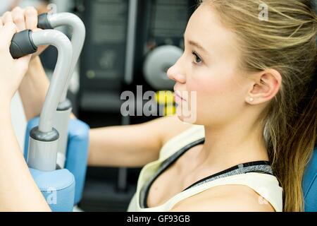 PROPERTY RELEASED. MODEL RELEASED. Young woman using butterfly machine in gym. Stock Photo