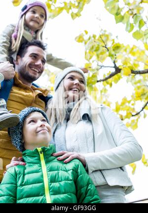 MODEL RELEASED. Family together in park smiling and looking away, birdhouse in background. Stock Photo