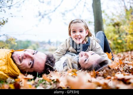 MODEL RELEASED. Family lying on dried leaves in autumn. Stock Photo