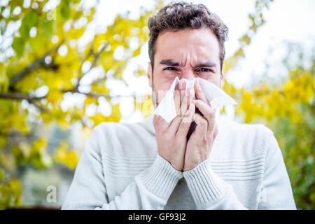 MODEL RELEASED. Young man sneezing, portrait, close-up. Stock Photo