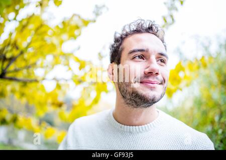 MODEL RELEASED. Young man looking away and smiling, close-up. Stock Photo