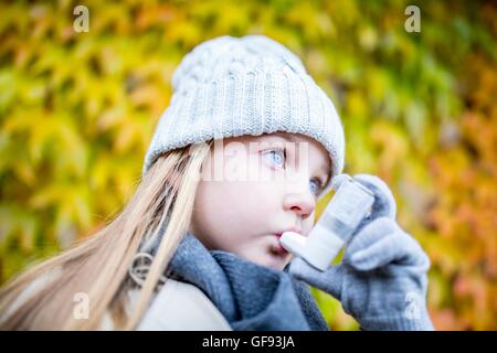 MODEL RELEASED. Young girl using asthma inhaler, close-up. Stock Photo