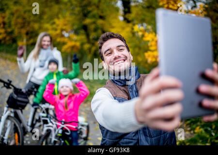 MODEL RELEASED. Smiling man taking photo of family. Stock Photo