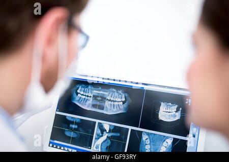 MODEL RELEASED. Two dentist smiling and examining medical x-ray in hospital. Stock Photo