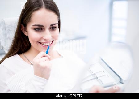 MODEL RELEASED. Young woman using interdental brush in hospital. Stock Photo