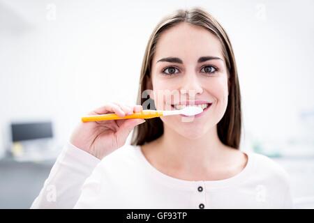 MODEL RELEASED. Young woman brushing teeth, portrait, close-up. Stock Photo