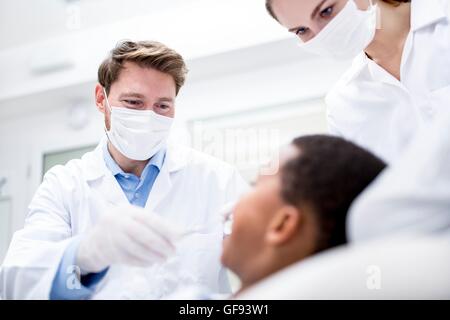 MODEL RELEASED. Dentist examining patient with his assistance. Stock Photo