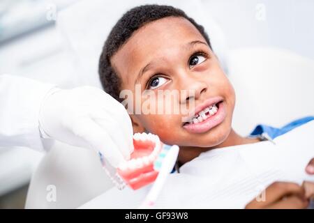 MODEL RELEASED. Dentist showing boy how to brush his teeth. Stock Photo