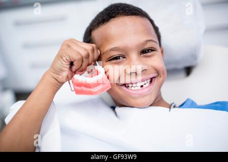 MODEL RELEASED. Portrait of boy holding dentures, smiling. Stock Photo