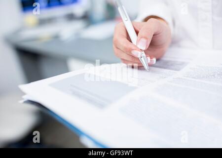 Close-up of dentist's hand writing on file. Stock Photo