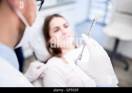 MODEL RELEASED. Dentist holding syringe in dentist clinic. Stock Photo