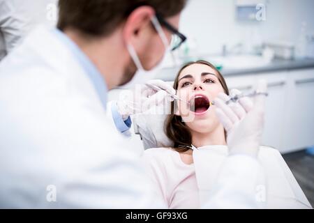 MODEL RELEASED. Dentist giving anaesthesia to patient before dental surgery Stock Photo