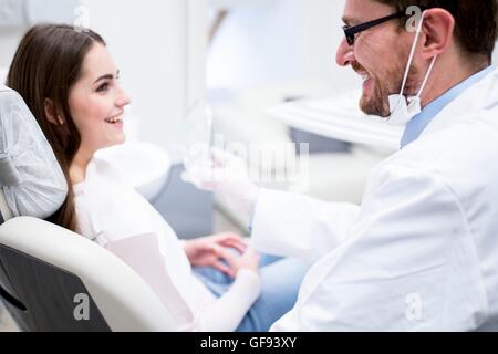 MODEL RELEASED. Dentist and patient smiling in dentist clinic. Stock Photo