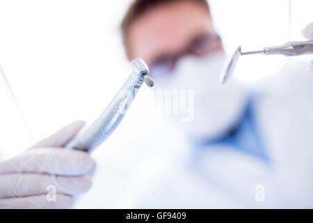 MODEL RELEASED. Dentist holding dental drill and angled mirror. Stock Photo