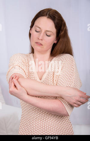 MODEL RELEASED. Young woman holding her elbow. Stock Photo