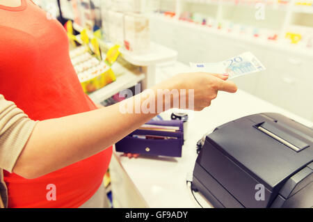 pregnant woman with money at cashbox in drugstore Stock Photo