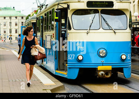 Goteborg, Sweden - July 25, 2016: Real people in everyday life. Lovely woman in glasses walking beside an electric tram.