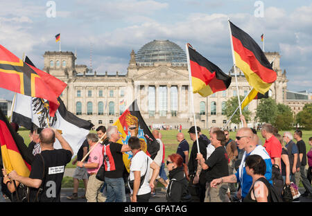 Berlin, Germany. 30th July, 2016. Pariticpants in a demonstration of right-wing populist and extremist groups walk past the Reichstag building in Berlin, Germany, 30 July 2016. Photo: PAUL ZINKEN/dpa/Alamy Live News Stock Photo