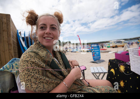 Harlyn Bay, Near Padstow, Cornwall, UK. 31st July, 2016. 'Jarley' spends her day making Hair braids for the visitors to Harlyn Bay Beach, whislt enjoying the Beautiful sunny weather at Harlyn Bay, Near Padstow, Cornwall, Credit:  @camerafirm/Alamy Live News Stock Photo