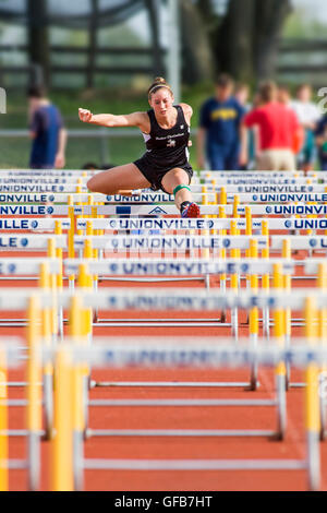 Female hurdler competes during a high school track & field meet Stock Photo