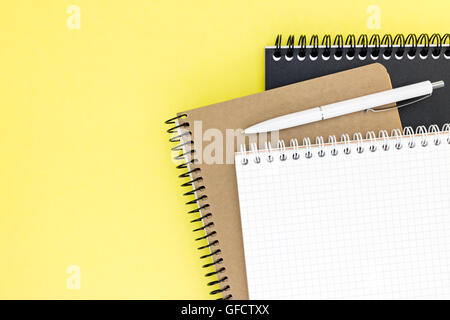 three notepads one with open blank page on yellow surface background Stock Photo