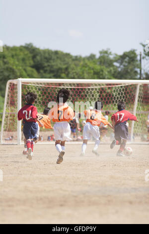 Boy's soccer trying to bring a ball to the goal Stock Photo