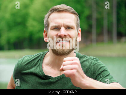 Man running outdoors closeup. Male athlete jogging outside in park. Healthy lifestyle concept. Stock Photo