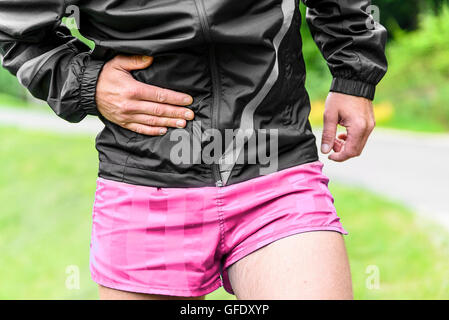 Man runner side cramps after running outdoors Stock Photo