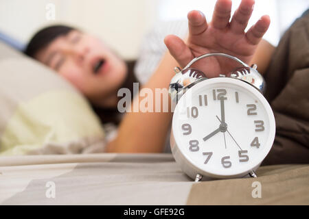 Young woman getting stressed about waking up too early, shallow depth of field, focus on foreground Stock Photo