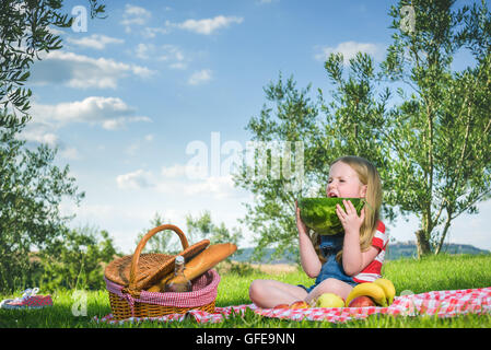 Small beautiful blond girl doing picnic in the landscape of Tuscan countryside. Stock Photo