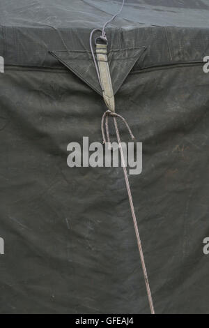 Guy rope fixing of an old canvas army field tent - as a metaphor for the concept of tied down, fixed, held fast, restrained. Stock Photo