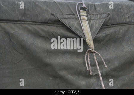 Guy rope fixing of an old canvas army field tent - as a metaphor for the concept of tied down, fixed, held fast, restrained. Stock Photo