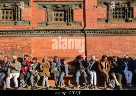 Nepalese men gathering and wearing Dhaka Topi (traditional Nepalese hat) at sunset at Durbar Square in Patan, Nepal Stock Photo