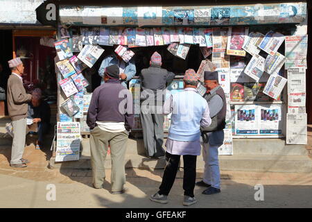 Nepalese men gathering and wearing Dhaka Topi (traditional Nepalese hat) in front of a newspaper kiosk in Patan, Nepal Stock Photo