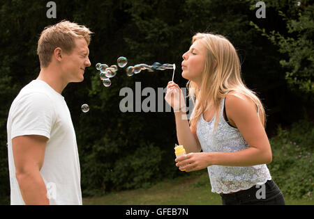 TEENAGER BLOWING BUBBLES   A teenage girl blowing bubbles at her boyfriend Stock Photo