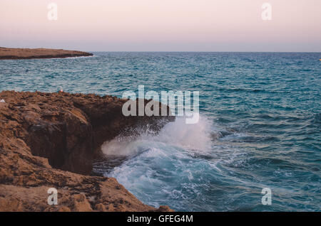 Ocean wave breaking the sea water on the rocky shore Stock Photo