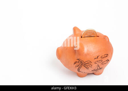 Saving money into a traditional clay piggy bank for holidays - high angle Stock Photo