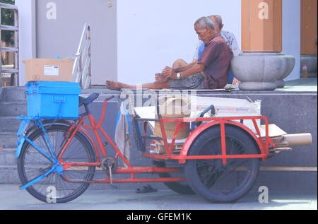 Men rest from cardboard collection job in Chinatown in Singapore. Stock Photo