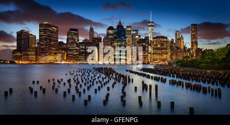 Panoramic of Lower Manhattan Financial District at twilight with old pier wood pilings and World Trade Center. New York City Stock Photo