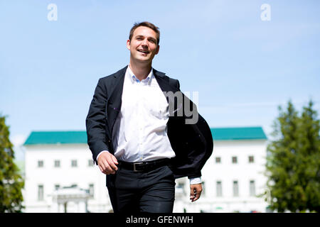 Close up portrait of a young business man in a dark suit and white shirt on the background of summer city Stock Photo