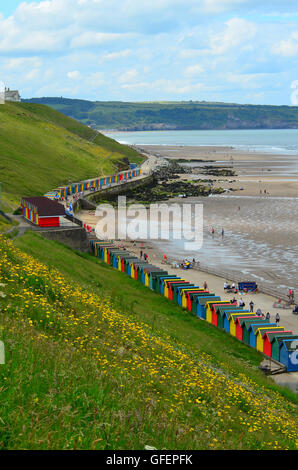 Multi-coloured beach huts at Whitby Beach, Whitby, Yorkshire, England, UK. Sandsend in the distance Stock Photo