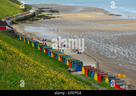 Multi-coloured beach huts at Whitby Beach, Whitby, Yorkshire, England, UK. Sandsend in the distance Stock Photo