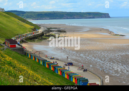 Multi-coloured beach huts at Whitby Beach, Whitby, Yorkshire, England, UK. Sandsend in the distance Stock Photo