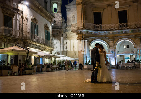 A bride and groom pose for a photographer at Piazza Plebiscito in Martina Franca, Puglia, Italy Stock Photo